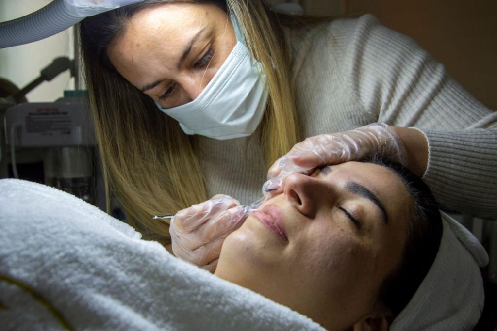 Client receiving a personalized acne treatment in a modern skincare clinic.